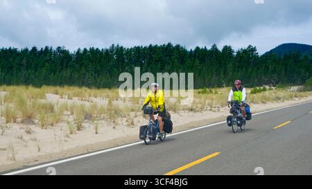 Two men riding fully loaded touring bicycles on tour of the Oregon coast. Sandlake, Tillamook County, Oregon, USA Stock Photo