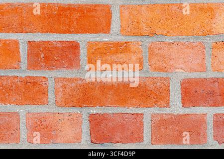 A red brick wall emphasizing the rhythm of repeating rectangles and the contrasting gray mortar, symbolizing strength, balance, and simplicity. Stock Photo