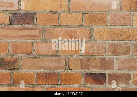 Close-up photo of weathered brick wall with warm colors and visible mortar cracks. Stock Photo