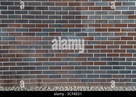 A clean, full-frame image of a dark modern brick wall, showcasing geometric precision and minimal design. Stock Photo