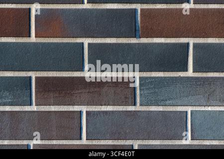 A tight closeup of a modern dark brick wall with clean mortar joints. The regular geometric pattern and muted tones create a minimalist, contemporary Stock Photo