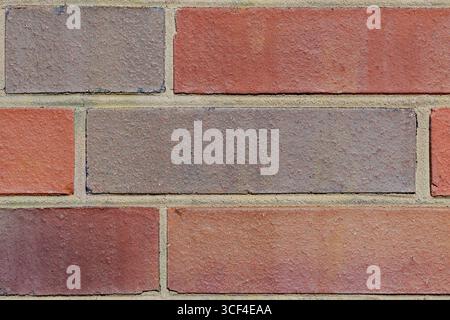 Closeup of a brick wall where red and gray bricks alternate, creating a play of color and texture. Slight imperfections in the surface. Stock Photo