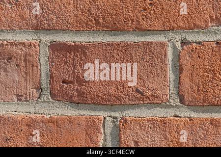 Aged red brick wall with imperfections, pores, and weathered textures. The uneven surfaces tell a quiet story of time and endurance. Stock Photo