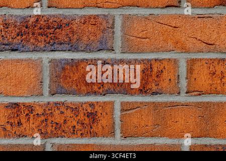 Red brick wall with visible stains, rough texture, and gray mortar lines. Stock Photo