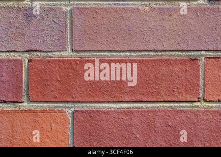 A closeup of a red brick wall with subtle brown and violet undertones. The simple, muted palette and even structure convey calmness and stability. Stock Photo