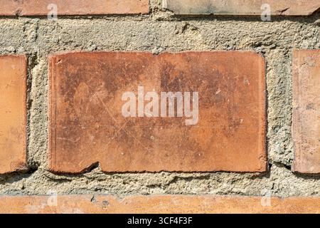 A closeup of an old brick shows scratches, chips, and rough mortar edges, telling a story of age and resilience, capturing imperfection as beauty. Stock Photo