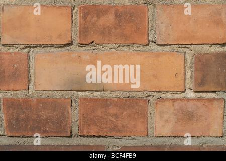 A detailed view of an old brick wall, showing weathered surfaces, subtle discolorations, and rough mortar. Stock Photo