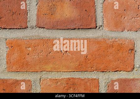 Aged red brick wall, rough textures, subtle cracks, weathered surfaces and one large central brick. Stock Photo