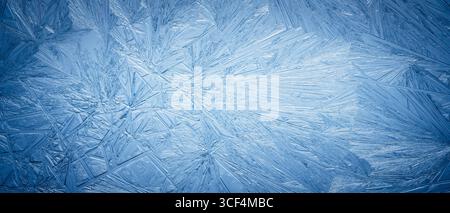 Snowflake frost patterns on glass. Vivid ice crystal textures on clear glass window. Frozen surface, snow flake structure, or freezing cold winter bac Stock Photo