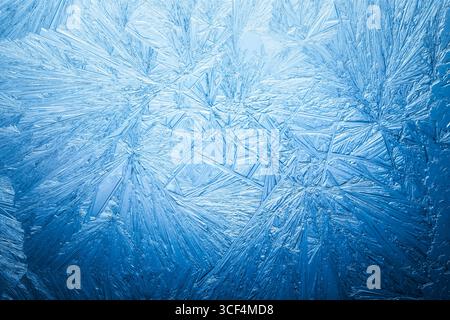 Snowflake frost patterns on glass. Vivid ice crystal textures on clear glass window. Frozen surface, snow flake structure, or freezing cold winter bac Stock Photo