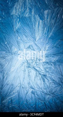 Snowflake frost patterns on glass. Vivid ice crystal textures on clear glass window. Frozen surface, snow flake structure, or freezing cold winter bac Stock Photo