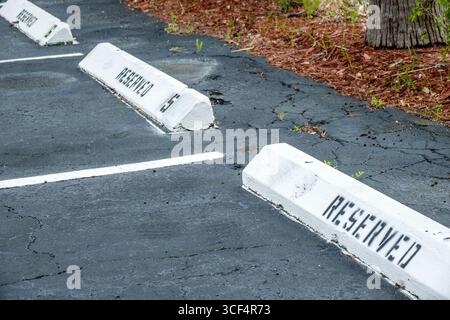 South Miami Florida,reserved parking space,painted curb stop concrete block,black stencil lettering reserved,asphalt pavement surface,cracks in parkin Stock Photo