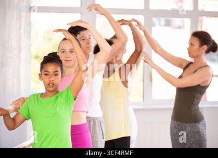 Black teen girl mastering third position at barre in ballet studio Stock Photo