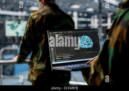 Close up of server hub employee in soldier uniform using laptop, running AI tools. Army information technology specialist in data center deploying machine learning models for battlefield analytics Stock Photo
