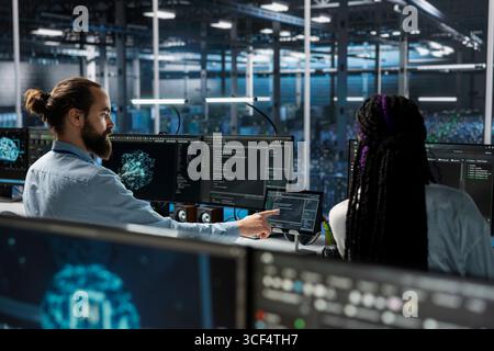 Admins in high tech data center installing upgraded server racks systems helped by AI technology. Server room IT specialists upgrading enterprise networks gear using artificial intelligence Stock Photo