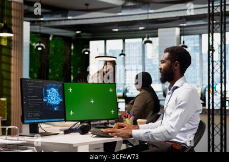 Technician using green screen PC to code, testing AI applications to minimize bugs, improving system stability. IT specialist in tech startup office optimizing performance using chroma key computer Stock Photo
