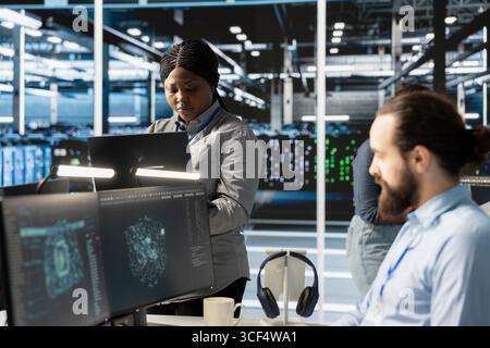 Engineers doing maintenance on blade servers supplying compute power for AI data processing and inference workloads. IT experts overseeing data center arrays managing training datasets Stock Photo
