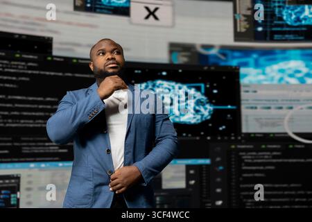 African American IT engineer analyzing programming language for automation, data science with a futuristic interface behind him. Male tech professional thrives with AI and code snippets. Stock Photo