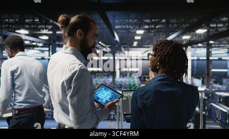 Data center system administrators performing maintenance on supercomputers used for AI. Engineering team managing server hub rigs used for deep learning training, Stock Photo