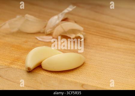 Closeup of Garlic Cloves on Wooden Cutting Board Stock Photo