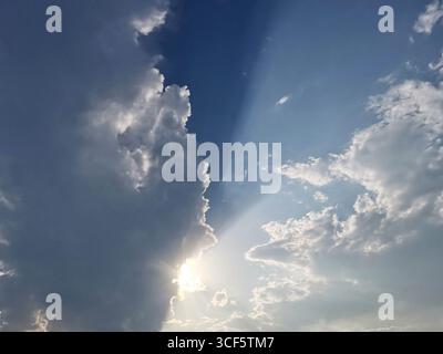 Majestic dramatic cloud formation showcases sunlight breaking through, illuminating the sky with rays of light, creating captivating and serene atmosp Stock Photo