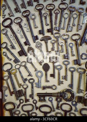 Old keys of different centuries, shapes, sizes, colors, materials are neatly laid out on gray background. Collection, historical heritage, elements of Stock Photo