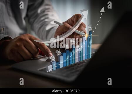 Financial growth concept shown by rising bar chart with percentage icons as a person analyzes data using a digital pen on a laptop in a modern workspa Stock Photo
