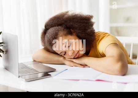 Exhausted African American woman sleeping on desk near laptop Stock Photo