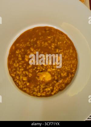 Mussels in broth served in white ceramic bowl surrounded by red chili ...