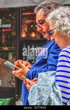 Mature couple looking at their smartphones (for directions?) in old quarter of Tours, Indre-et-Loire (37), France. Stock Photo