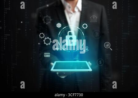 Professional man presenting a digital pad with security symbols in a high-tech environment Stock Photo