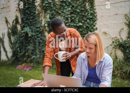 Two businesswomen collaborating on a project in a garden Stock Photo