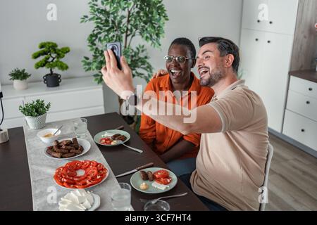 Happy couple taking selfie while having lunch at home Stock Photo