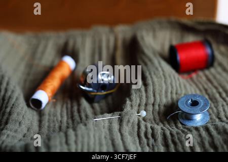 Needle, bobbin, and thread on cloth, essential accessories for sewing and DIY projects. Stock Photo