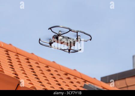 Roof inspection with drone: Drone flying over the tiled roof of a residential building Stock Photo