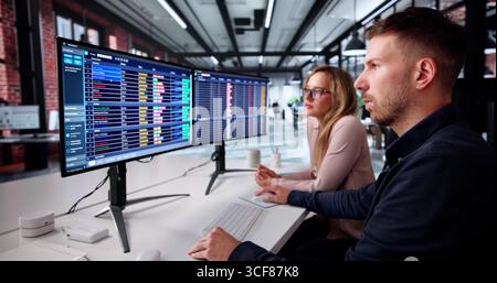 Man And Woman Study Spreadsheets On Computer In Office. Stock Photo