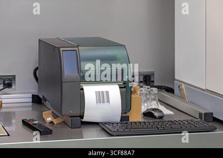 Barcode Stickers Industrial Printer With Keyboard and Remote Control at Desk Stock Photo