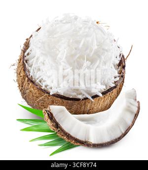 Grated coconut pulp in cracked coconut shell with green leaves and piece of coconut near it isolated on white background. Stock Photo