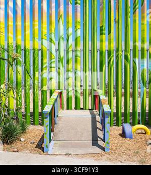 A wooden "bridge" with painted railings leads to decorated border wall near the friendship garden section of the wall in the Playas de Tijuana. Stock Photo
