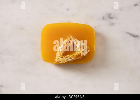 Turmeric soap bar on marble white background. Organic skincare product and bath accessories. View from above. Vertical. Stock Photo