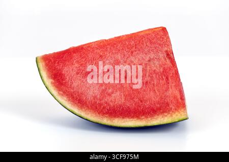A fresh sliced seedless watermelon with vibrant red flesh and green rind, isolated on white background, showcasing juicy texture and summer freshness Stock Photo