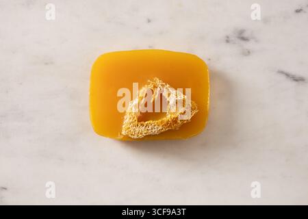 Turmeric soap bar on marble white background. Organic skincare product and bath accessories. View from above. Vertical. Stock Photo