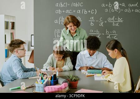 Middle Aged Caucasian Woman Teaching Diverse Children Solving Math Problems Stock Photo