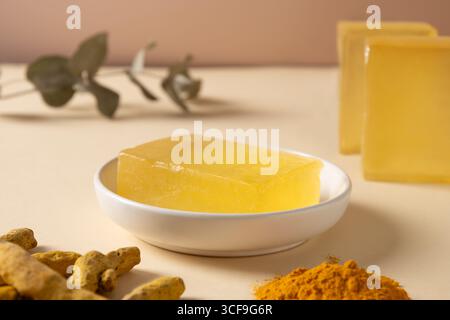 Handmade soap bars, powder and turmeric root on beige background. Organic skincare product perfect for wellness, beauty, and organic body care concept Stock Photo