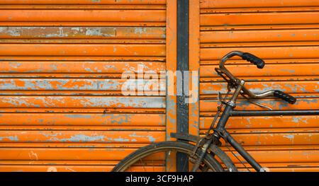 Closeup of old rusty bicycle on an orange background. Stock Photo