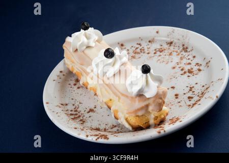 Elegant Eclair with Whipped Cream and Blueberries on a Decorative Plate Stock Photo