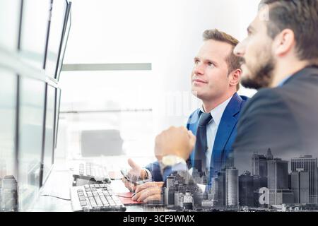 Successful businessmen trading stocks. Stock traders looking at graphs, indexes and numbers on multiple computer screens. Colleagues in traders office. Business success. Stock Photo