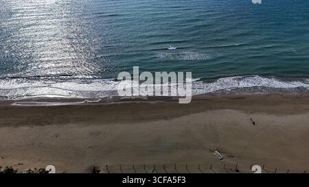Waves lapping gently on a serene beach at sunset, inviting tranquility and reflection in a coastal paradise Stock Photo