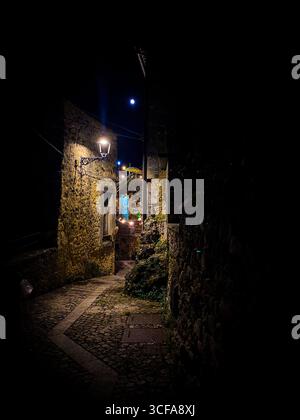 Moonlight illuminating narrow cobblestone pathway winding through medieval Pretoro village, casting soft shadows across ancient Italian landscape Stock Photo