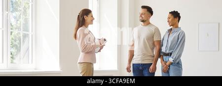 Man and woman talking with female realtor in new house and ready to become homeowners. Stock Photo